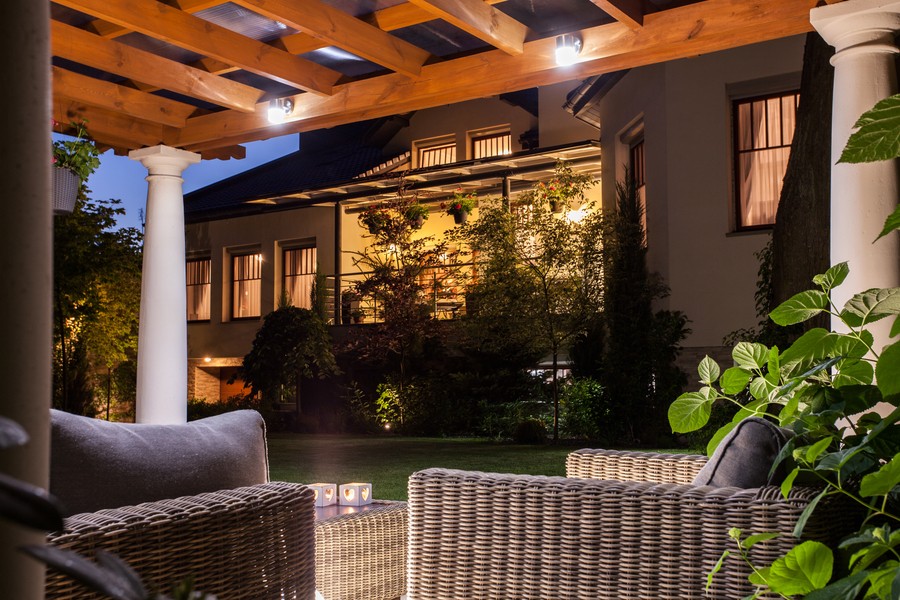 A roofed outdoor space illuminated by landscape lighting 