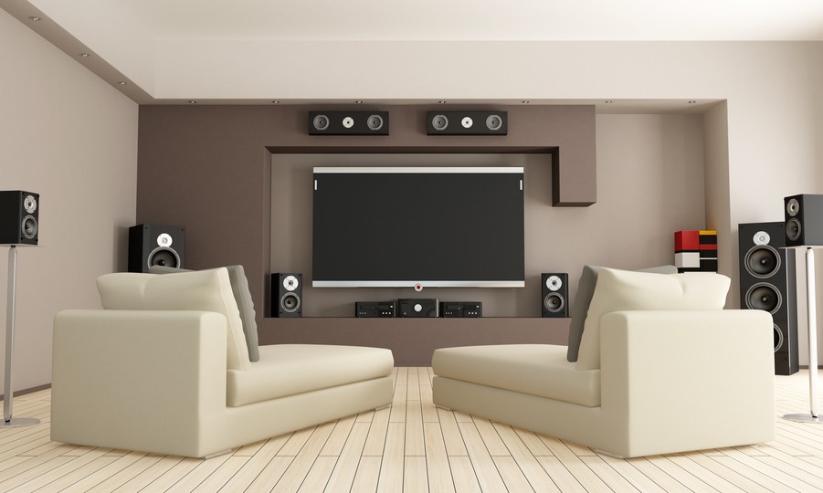  Image is of a living room with speakers and a flat-screen TV mounted on the wall.