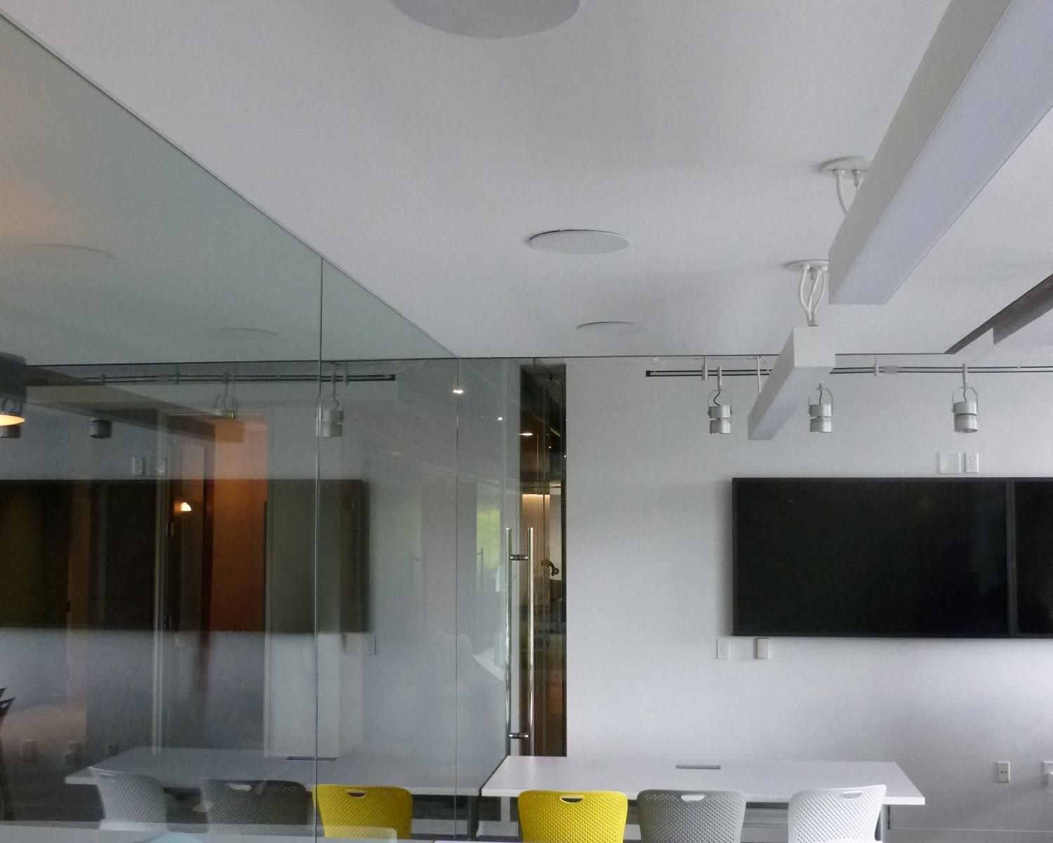 white room with tv, lighting, and speakers in the ceiling